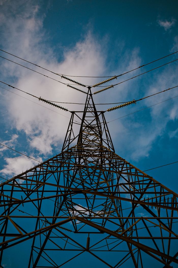 A dramatic view of a steel power pylon reaching into the sky, showcasing modern energy infrastructure.
